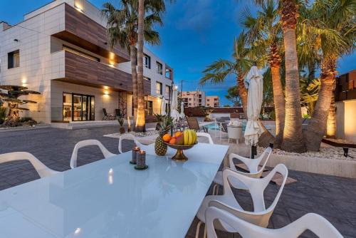 a patio with a white table and chairs and palm trees at [Lusso e relax] con piscina a 2 minuti dal mare in Miami Platja
