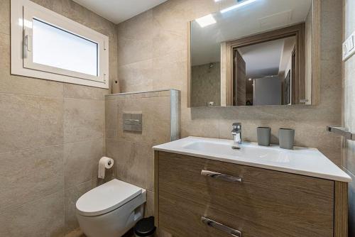 a bathroom with a toilet and a sink and a mirror at [Lusso e relax] con piscina a 2 minuti dal mare in Miami Platja