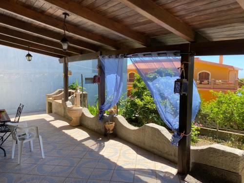 eine Terrasse mit einem Baldachin, einem Tisch und Stühlen in der Unterkunft Casa Vacanza Sa dommu de Teresa in Nebida