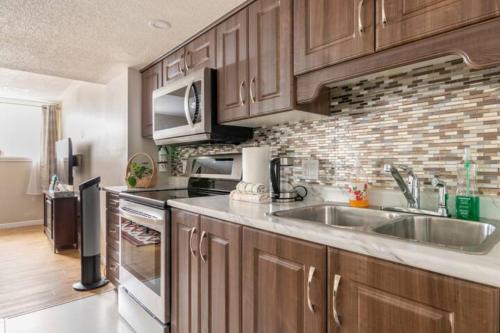 una cocina con armarios de madera y una pared de ladrillo en Self check-in spacious apartment with full Kitchen en Ottawa