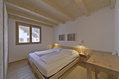 a bedroom with a bed and a desk and a window at Chesa Piz Chalchagn - Pontresina in Pontresina
