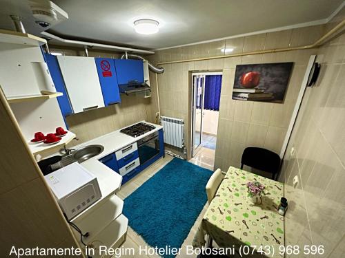 uma pequena cozinha com um lavatório e uma mesa em Apartament Uvertura Mall/Lidl cu parcare gratuita em Botoşani