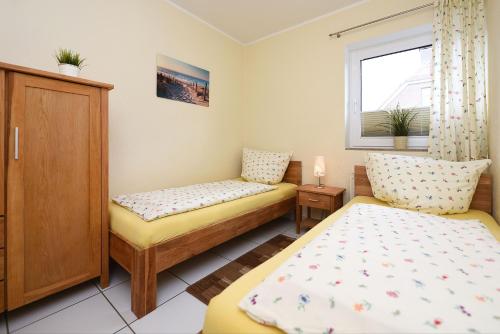 Cette petite chambre comprend 2 lits et une fenêtre. dans l'établissement Wohnung Typ A im Haus Friedeburg EG, Carolinensiel, à Carolinensiel
