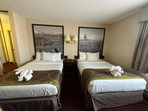 a hotel room with two beds with towels on them at Super 8 by Wyndham Lethbridge in Lethbridge