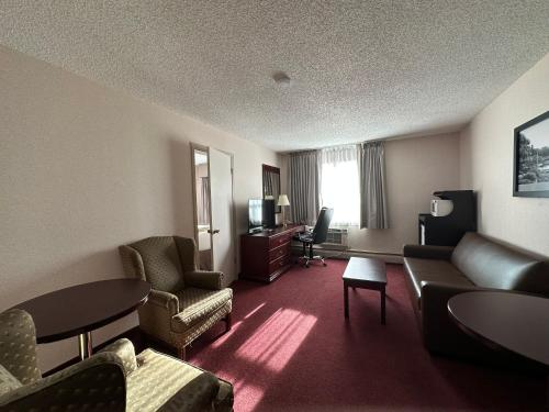 a hotel room with a couch and chairs and a television at Super 8 by Wyndham Lethbridge in Lethbridge