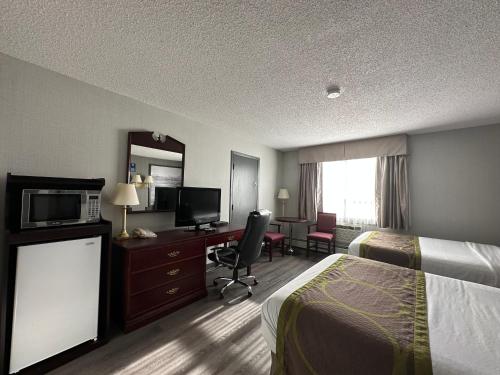 a hotel room with a bed and a desk with a television at Super 8 by Wyndham Lethbridge in Lethbridge