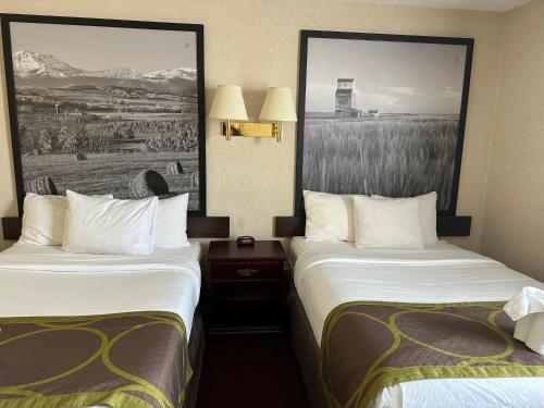 a hotel room with two beds and a picture on the wall at Super 8 by Wyndham Lethbridge in Lethbridge