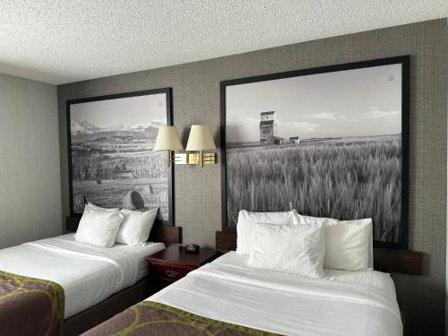 a hotel room with two beds and a painting on the wall at Super 8 by Wyndham Lethbridge in Lethbridge