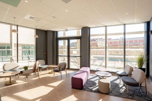 - une salle d'attente avec des tables, des chaises et des fenêtres dans l'établissement B&B HOTEL Toulon Centre Gare, à Toulon