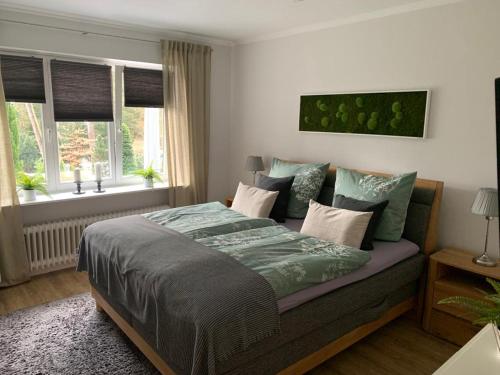 um quarto com uma cama com um edredão verde e janelas em Ferienhaus Bendestorf, Waldweg 38,Nähe Hamburg em Bendestorf