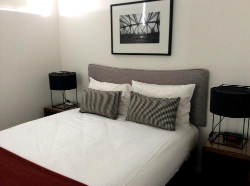 a bedroom with a white bed with two lamps at Morgan Suites in Brisbane