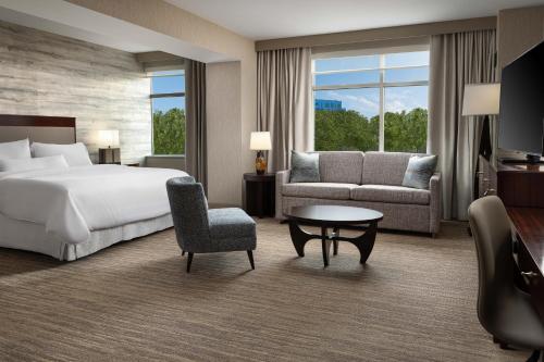 a hotel room with a bed and a couch and a table at The Westin Reston Heights in Reston