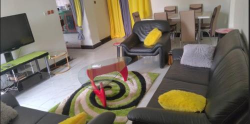 a living room with a couch and chairs and a tv at Studios-Appartements meublés Makepé BM in Douala
