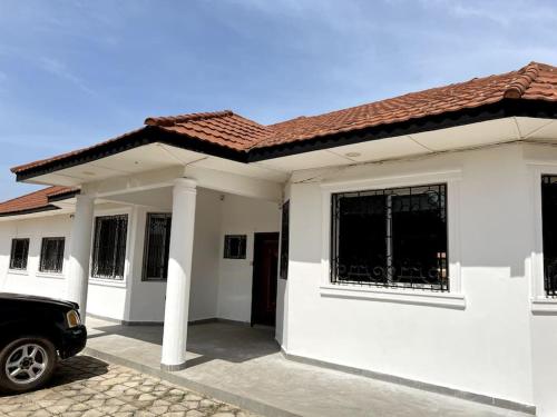 a white house with a car parked in front of it at Laffie House in Sukuta