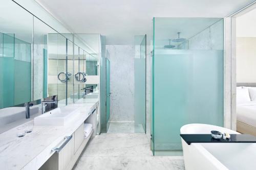 a bathroom with two sinks and a shower at The Stones Hotel - Legian Bali, Autograph Collection in Kuta