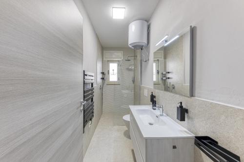 a white bathroom with a sink and a mirror at Appartamento lussuoso in Salve