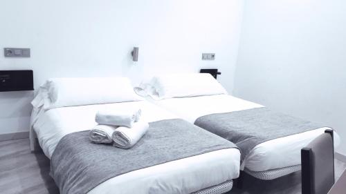 two beds in a hotel room with white walls at Hostal Doña Isabel in Majadahonda
