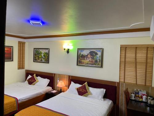 サパにあるHotel Sao Xanhのベッド2台と緑の光が備わるホテルルームです。