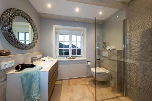 uma casa de banho com um chuveiro, um WC e um espelho. em Haus Sylter Momente em Westerland
