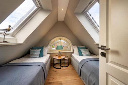 two beds in a attic room with windows at Haus Sylter Momente in Westerland