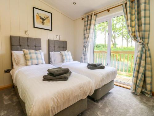 two beds in a bedroom with a large window at Robin Lodge in Skipton