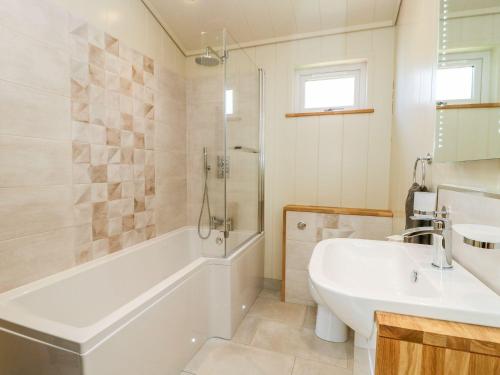 La salle de bains est pourvue d'une baignoire, d'un lavabo et d'une douche. dans l'établissement Robin Lodge, à Skipton