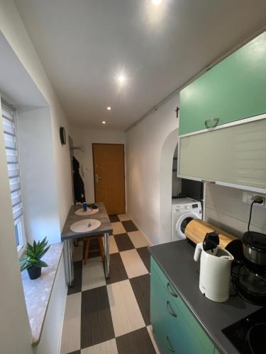 a kitchen with green cabinets and a checkered floor at Apartament Osiedle Ogrodowe in Kraków