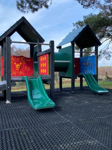 a playground with two slides in a park at Scandinavian Village Ltd in Aviemore