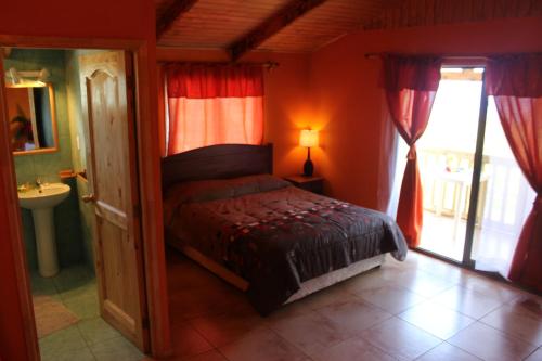 ein Schlafzimmer mit einem Bett und ein Bad mit einem Fenster in der Unterkunft Chez Jérôme in Hanga Roa
