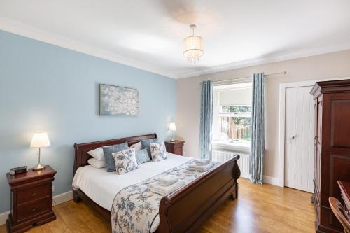 Un dormitorio con una cama con paredes azules y una ventana en Rowan Tree Cottage with Hot Tub, en Cupar