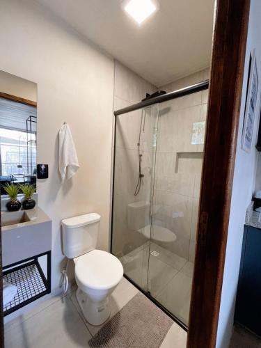 uma casa de banho com um WC e uma cabina de duche em vidro. em LOFT BC em Balneário Camboriú