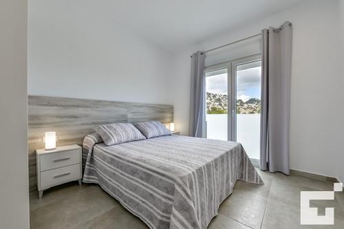 een witte slaapkamer met een bed en een raam bij Villa Marigold - Grupo Turis in Benissa