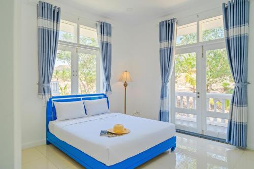 ファンティエットにあるCasa Villa - Floral Park- Sealinks City Resortの青と白のベッドルーム(ベッド1台、窓付)