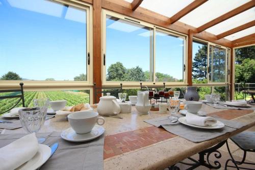 une table en bois avec des assiettes, des tasses et des fenêtres dans l'établissement Les Gagères, à Puligny-Montrachet