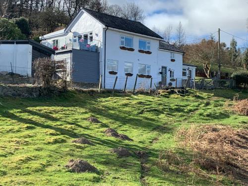 a white house with a yard in front of it at Broombush B & B & Yr Nyth Shepherds Hut in Aberhafesp