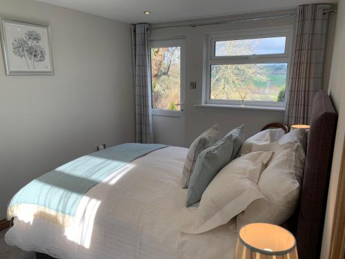 a bedroom with a large white bed with a window at Broombush B & B in Aberhafesp