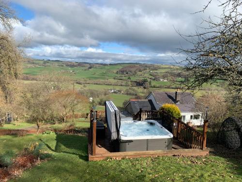 a hot tub in the backyard of a house at Broombush B & B & Yr Nyth Shepherds Hut in Aberhafesp