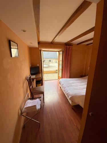 1 dormitorio con 1 cama, 1 silla y 1 ventana en Au Bon Accueil, en Arvieu