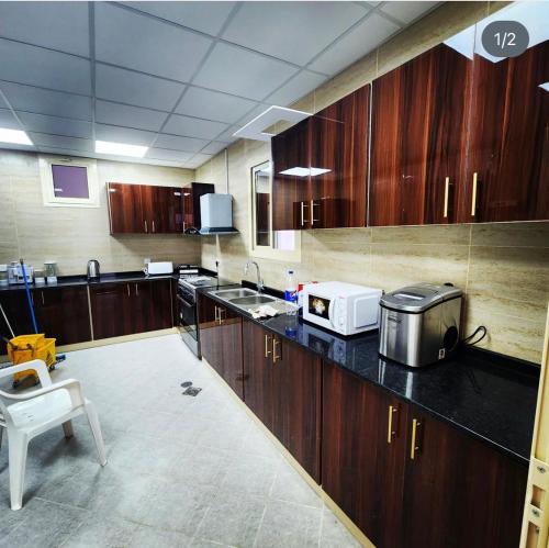 a large kitchen with wooden cabinets and a microwave at UptownRak FarmHouse in Diqdāqah