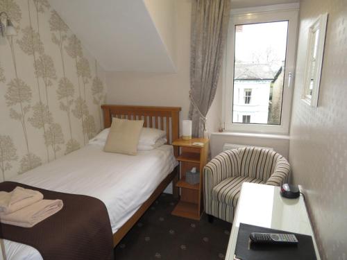 a bedroom with a bed and a chair and a window at Hillside Bed & Breakfast in Kendal