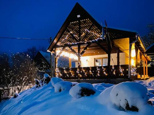 a house covered in snow at night with lights at Aprócska kulcsosház - Guesthouse in Inlăceni