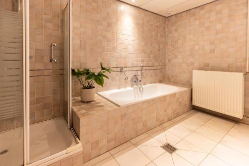 y baño con bañera, ducha y lavamanos. en Bed & Breakfast Rijsterbosch, en Rijs