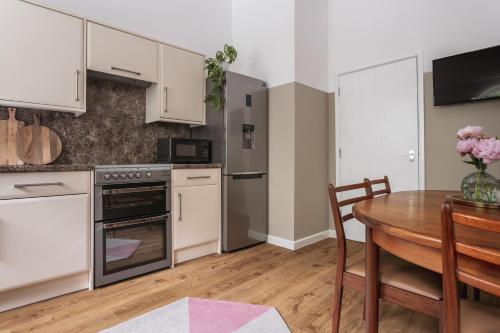 a kitchen with white cabinets and a wooden table at 14 Church Street- close to Windermere Train Station in Windermere