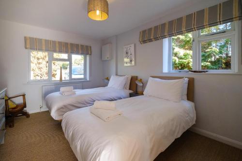 two beds in a room with two windows at Lowlands in Thorpeness