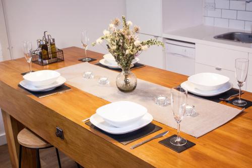 a table with plates and glasses and a vase with flowers at Spacious Industrial style Apartment in London