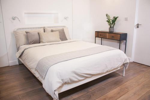 a bedroom with a large white bed and a table at Spacious Industrial style Apartment in London