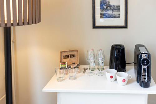 a counter with wine glasses and coffee cups on it at Bed & Breakfast Rijsterbosch in Rijs