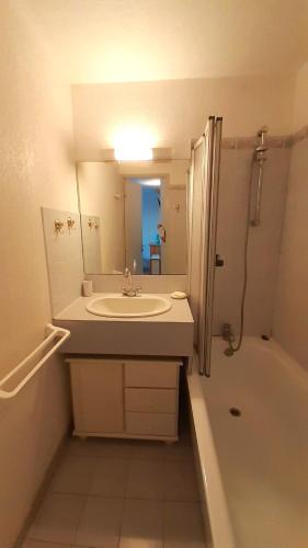 une salle de bain avec un lavabo, une baignoire et un miroir dans l'établissement ARCHIPEL III Joli T2 piscine proche plage Richelieu Cap d'Agde, au Cap d'Agde
