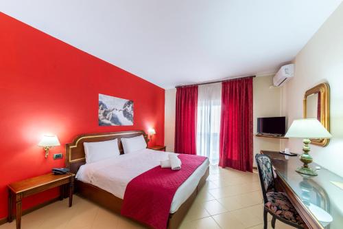 a bedroom with a red wall with a bed and a table at Hotel Sakura in Torre del Greco