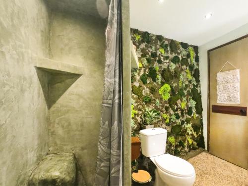 a bathroom with a toilet and a plant wall at Papou Cottage in Pelekas